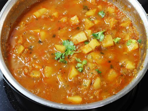 adding coriander leaves to potato curry